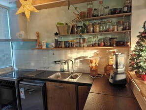 A kitchen with a built-in oven, a dishwasher, a sink, a coffee maker, a blender, and a Christmas tree.