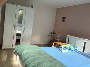 Un dormitorio con una cama, un armario, una mesita de noche y una pared con un póster.
