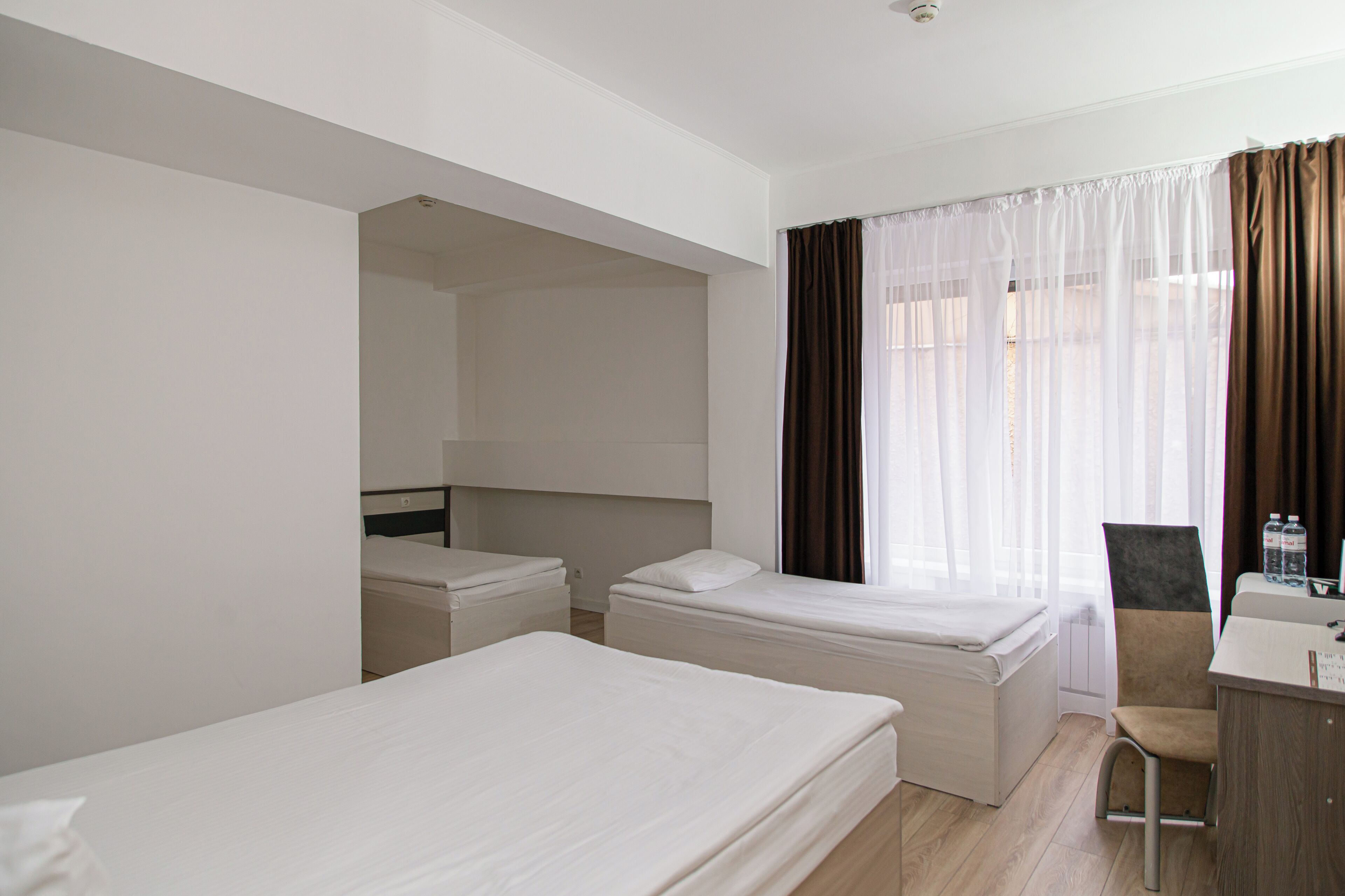 A hotel room with two beds, a desk, and a chair.