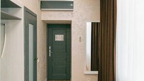 A hallway with a wooden floor, a dark door, and a mirror on the wall. - ASTRA HOTEL (Almaty)