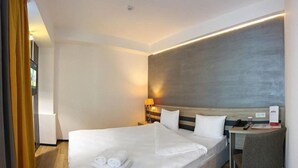 A hotel room with a large bed, bedside tables, a desk, and a chair. - ASTRA HOTEL (Almaty)