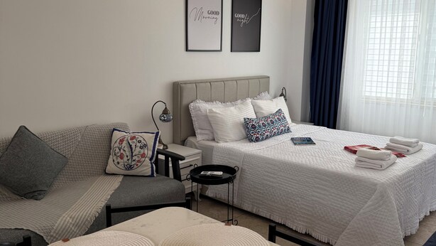 Une chambre d’hôtel moderne avec deux lits, un canapé, une petite table avec des sous-verres et des œuvres d’art encadrées accrochées au mur.