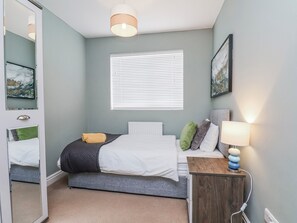 A bedroom with a bed, bedside table, lamp, window, and artwork. - 34 Fountain Close (Whitby)