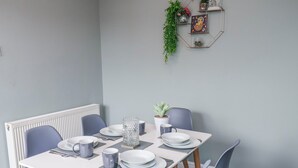 Een eettafel met borden, kopjes en een karaf, omringd door stoelen.