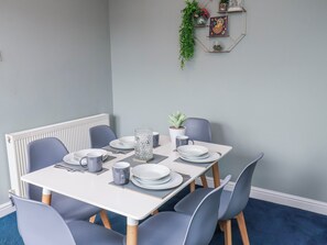 A dining table with plates, cups, and a pitcher, surrounded by chairs. - 34 Fountain Close (Whitby)