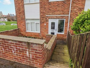 A brick house with a white door, a small window, and a wooden fence. - 34 Fountain Close (Whitby)