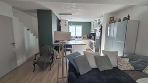 Een gezellig compacte ruimte met een bank, een eettafel en een keukenhoek.