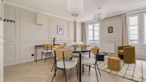 A room with a round table, chairs, a sofa, a patterned rug, and a window with curtains. - Charming apartment 2BDR/6PAX in the heart of Paris (Paris)