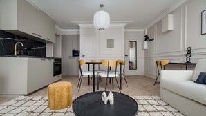 A modern living room with a round black coffee table, a sofa, a dining area with chairs, and a kitchen in the background. - Charming apartment 2BDR/6PAX in the heart of Paris (Paris)