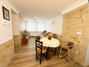 A dining area with a round table, chairs, and a stone wall. - Chalet 'Casa Rural La Abuela' with Mountain Views, Wi-Fi, and Air Conditioning (Mainar)