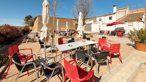 An outdoor patio with tables and chairs, umbrellas, and a building in the background.