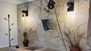 A stone wall with a rustic wooden bench, a hanging rope, and two potted plants.