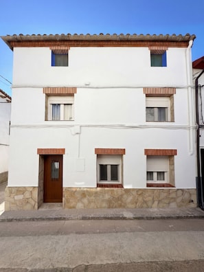 A two-story building with a stone base, multiple windows, and a brown door. - Chalet 'Casa Rural La Abuela' with Mountain Views, Wi-Fi, and Air Conditioning (Mainar)