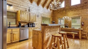 L’intérieur d’un chalet en bois comprend une cuisine, un coin repas et des tabourets de bar.