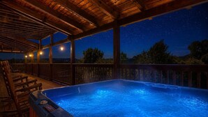 Un bain à remous sous une pergola en bois, avec vue sur le ciel étoilé.
