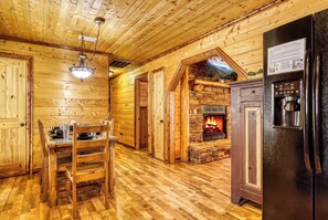 A wooden interior with a dining table, chairs, a fireplace, and a refrigerator. - Smoky Sunset Retreat, Hot Tub, Mountain Views, Free Tickets! (Sevierville)