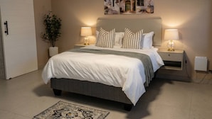 Een slaapkamer met een bed, nachtlampjes, een wandairconditioner, een potplant en kunstwerk.