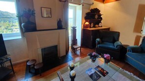 A cozy living room with a fireplace, a comfortable sofa, a coffee table with decorative items, and a view of the outdoors through a window.