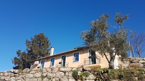 A stone wall with a building on top, featuring multiple windows and a balcony.