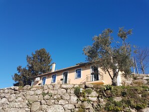 A stone wall with a building on top, featuring multiple windows and a balcony.