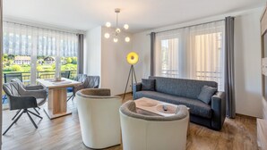 Ein modernes Wohnzimmer mit einer Couch, Sesseln, einem Esstisch und einer Stehlampe.