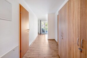 A hallway with wooden flooring, white walls, and a view of an outdoor area with tables and chairs. - Apartment 'Ferienwohnung Elbufer 3a' with Mountain View, Private Terrace and Wi-Fi (Stadt Wehlen)