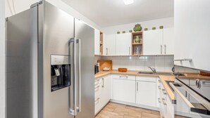Eine moderne Küche mit einem Edelstahl-Kühlschrank, einem eingebauten Backofen und einem Wasserspender.
