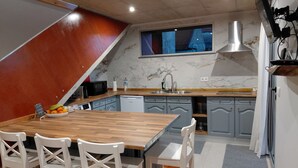 A kitchen with a wooden island, grey cabinets, a stainless steel sink, and a built-in microwave. - Casas do Pargo- Palheiro (Lombada Velha)