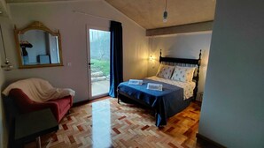 A bedroom with a bed, a chair, a mirror, and a door leading to an outdoor area. - Casas do Pargo- Palheiro (Lombada Velha)
