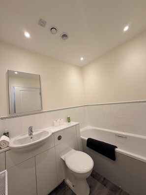 A bathroom with a sink, toilet, and bathtub, white tiles, and a mirror. - Inverness Retreat, visit the capital of the Highlands and relax! (Inverness)