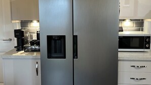 A stainless steel refrigerator with a water dispenser, a microwave, and a coffee maker on the counter. - Inverness Retreat, visit the capital of the Highlands and relax! (Inverness)