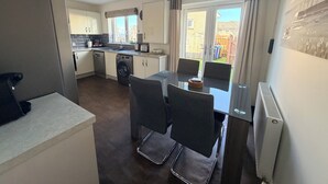 A compact kitchen with a dishwasher, washing machine, and a dining area with a table and chairs. - Inverness Retreat, visit the capital of the Highlands and relax! (Inverness)