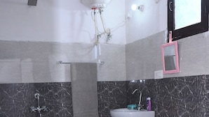 Ένα μπάνιο με τουαλέτα, νιπτήρα, ντους και στεγνωτήρα χεριών.