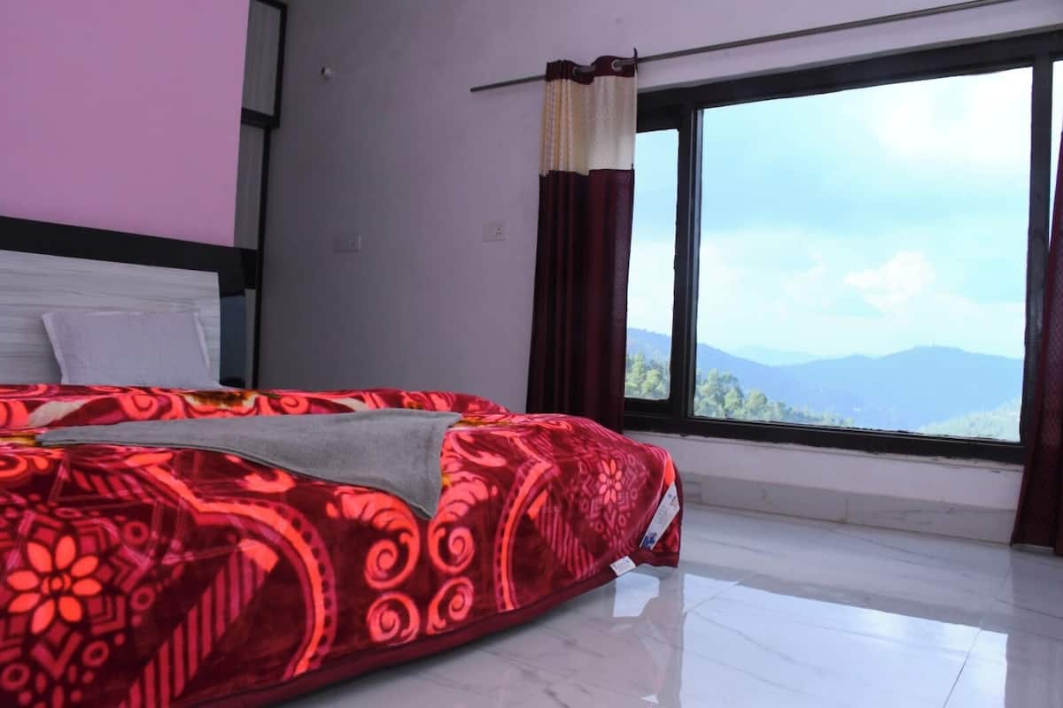 A bedroom with a large bed, a window with a view of mountains, and a curtain.