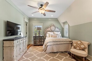 A bedroom with a bed, a dresser, a TV, a ceiling fan, and a window. - WaterSound Retreat | Private Pool | Near 30A Beach (Watersound)