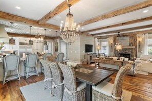 A spacious living area with a wooden ceiling, a dining table with wicker chairs, and a fireplace. - WaterSound Retreat | Private Pool | Near 30A Beach (Watersound)