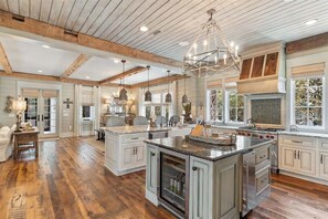 A spacious kitchen with wooden beams, a large island, and pendant lighting. - WaterSound Retreat | Private Pool | Near 30A Beach (Watersound)