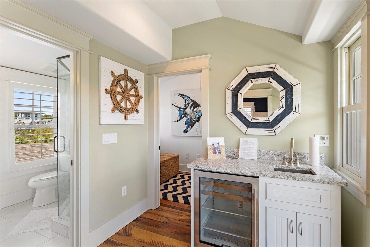 A modern bathroom with a glass shower enclosure, a white sink with a marble countertop, and nautical-themed wall art.