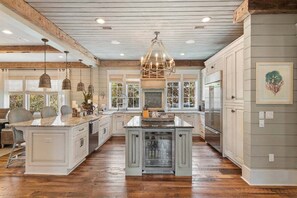 A spacious kitchen with a large island, wooden beams on the ceiling, and pendant lighting. - WaterSound Retreat | Private Pool | Near 30A Beach (Watersound)