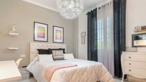 Un dormitorio con cama, mesitas de noche, cómoda y candelabro.