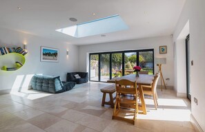 A modern interior with a skylight, a dining area, and a bookshelf. - Large 6BR House near Goodwood, Garden & Parking (Chichester)