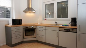 Een moderne keuken met roestvrijstalen apparatuur, een raam met zonwering en een houten aanrecht.