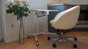 Een moderne keuken met een witte stoel, een witte tafel en een vaas met bloemen.