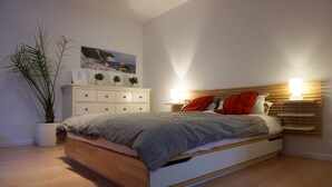 Een moderne slaapkamer met een houten bed, een witte dressoir en een potplant.