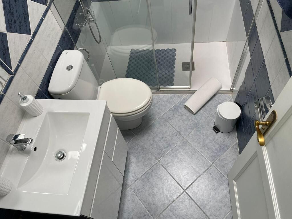 Une salle de bain équipée d’une douche, de toilettes, d’un lavabo et d’une serviette.