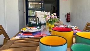 Ett träbord med färgglada muggar, en vas med blommor och en brandsläckare på väggen.