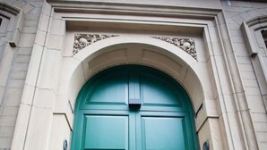 A green double door with a round handle, set within an arched stone frame. - Chic Manchester Chinatown Stay Shops Nightlife (Manchester)