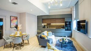 A modern living room with a dining area, grey sofa, coffee table, and a kitchen in the background. - Chic Manchester Chinatown Stay Shops Nightlife (Manchester)