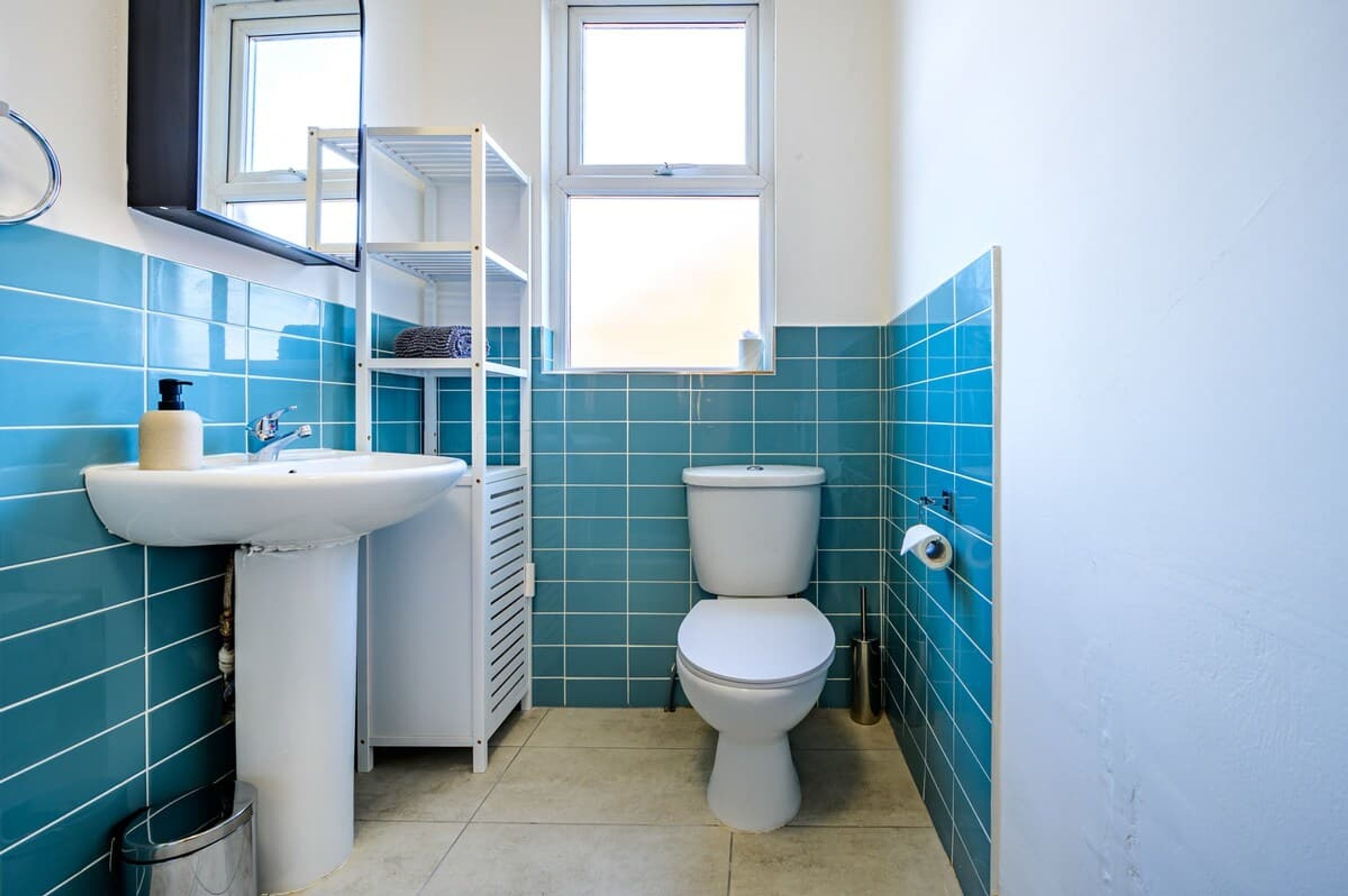 Een badkamer met een wastafel, toilet en een plankkast.