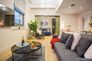 A modern living room with a glass coffee table, a sofa, and a TV mounted on the wall. - Stylish Modern Escape in the Heart of Manchester (Manchester)